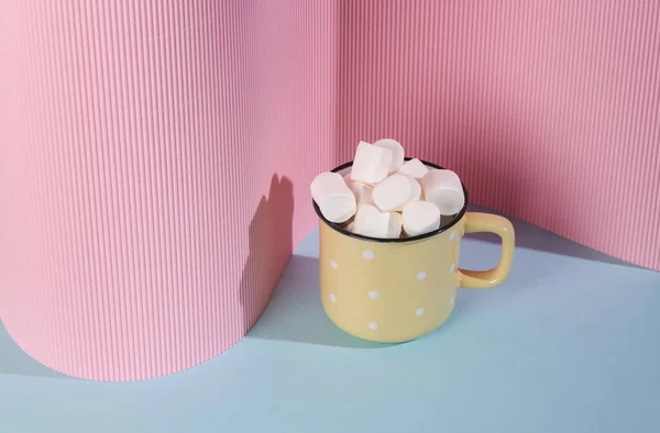 Cup with marshmallows on pink blue background. Creative layout