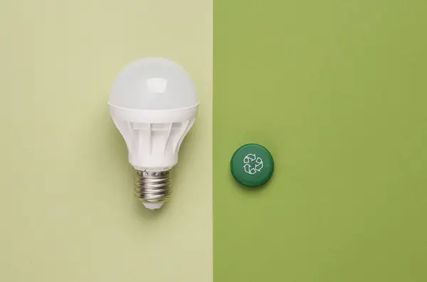 Plastic bottle cap with circular recycling symbol and light bulb on green background. Round recycle, eco concept