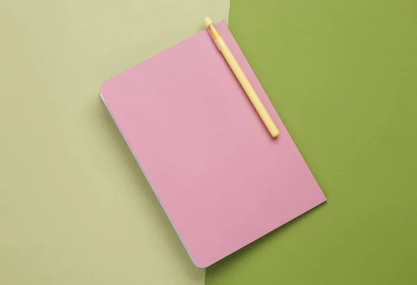 Cover of a pink notepad with pen on green background