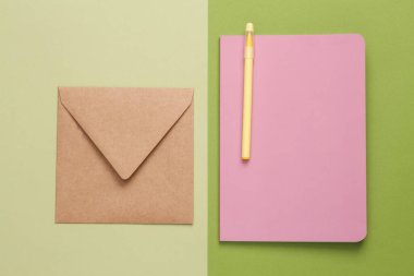 Craft envelope and diary on a green background. Top view