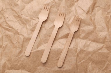 Set of wooden forks on crumpled craft paper background. Zero waste simple creative concept. Trendy wooden eco things. Top view, Flat lay