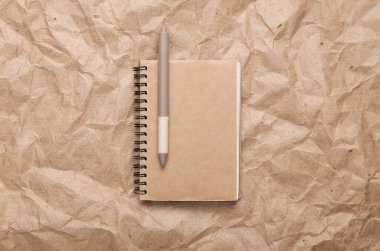 Craft notebook on crumpled craft paper background. Zero waste simple creative concept. Trendy wooden eco things. Top view, Flat lay