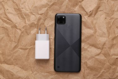 Charging adapter and smartphone on crumpled craft paper