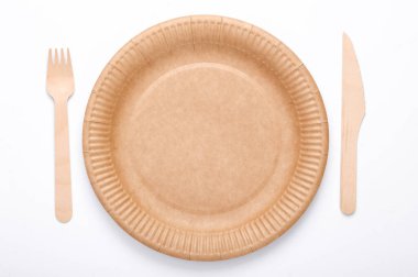 Eco products. No plastic. Zero waste. Craft disposable plate with wooden fork and knife on  white background. Natural materials. Top view