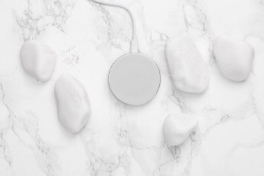 Wireless charging platform with Pebbles on a marble background. Top view