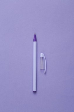 Purple pen with a cap on a purple background. Minimal concept