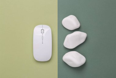 Creative composition with pc mouse and pebbles. Green two-tone background. Top view