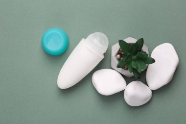 Antiperspirant roll with pebbles on green background. Beauty still life