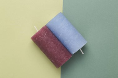 Two candles on green two tone background. Top view