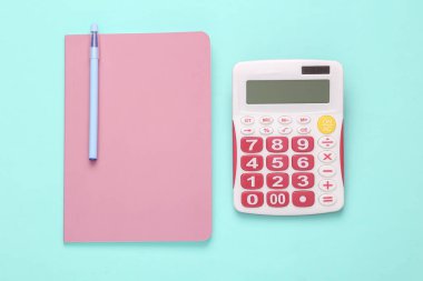 Calculator with notebook on a blue-pink pastel background. Business concept. Top view