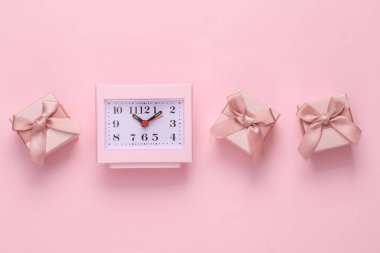 Clock with gift boxes on a pink background. Pink color trend.