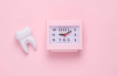 Time to visit the dentist. Clock with a tooth on a pink background