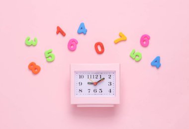 Education concept. Clock and many numbers on a pink background