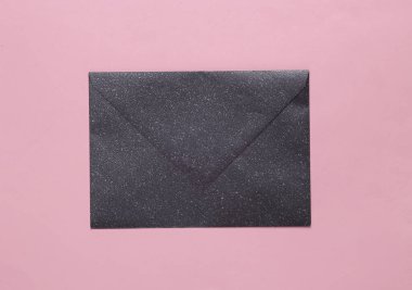 Black envelope with glitter on a pink background