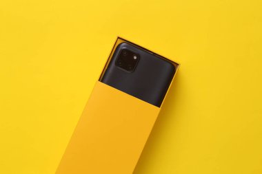 New unpacked modern smartphone in a yellow open box on a yellow background