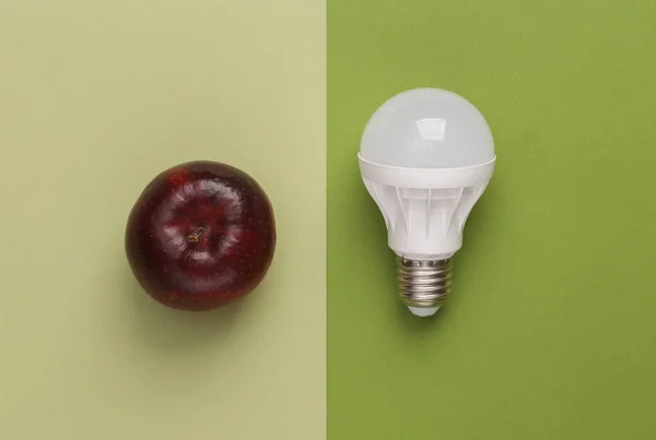 Fresh idea. Light bulb with apple on green background
