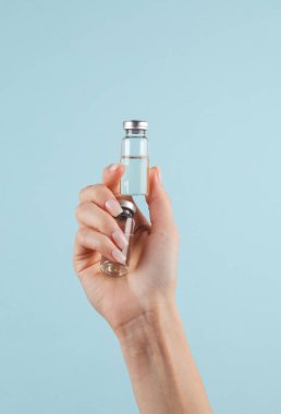 Aşı şişeleri mavi arka planda bir kadının elinde