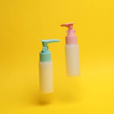 Sarı zemin üzerinde yükselen sabun ve krem şişeleri.