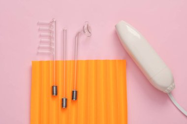 Pembe turuncu arka planda yerel darsonvalizasyon cihazı. Sivilce tedavisi, sorunlu deri. Üst Manzara. Düz konum