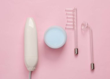 Pembe arka planda krema kavanozu ile yerel darsonvalizasyon için bir cihaz. Sivilce tedavisi, sorunlu deri. Üst Manzara. Düz konum