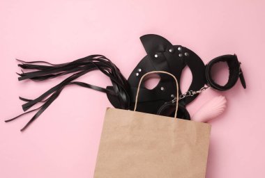 Pembe arka planda alışveriş çantasındaki seks dükkanından oyuncaklar. Üst görünüm