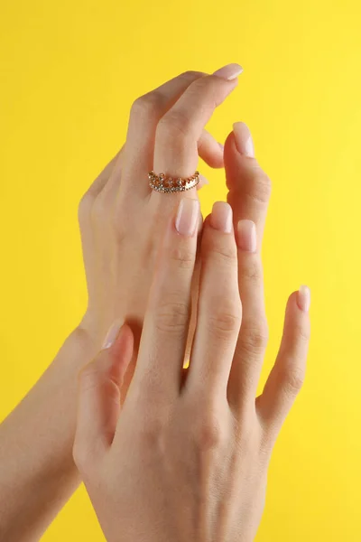 女性の指にダイヤモンドと王冠の形で黄金のリング 黄色の背景 — ストック写真