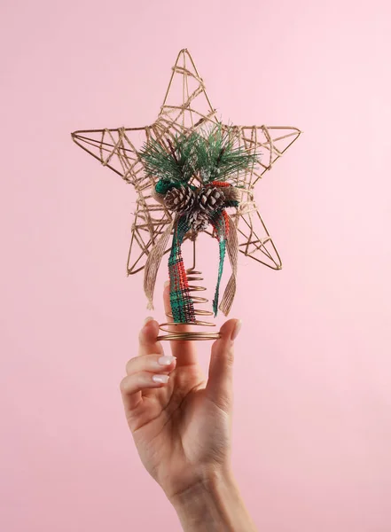 stock image Woman's hand holds craft homemade Christmas tree top star on a pink background