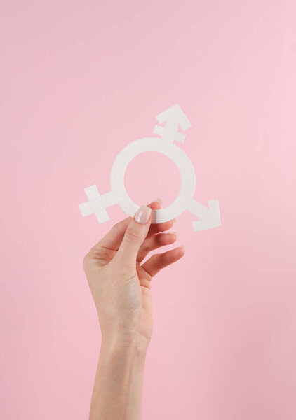 Transgender gender symbol in female hand on pink background