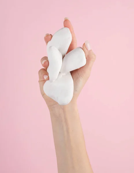 White pebbles in a female hand. Spa, beauty concept, pink background