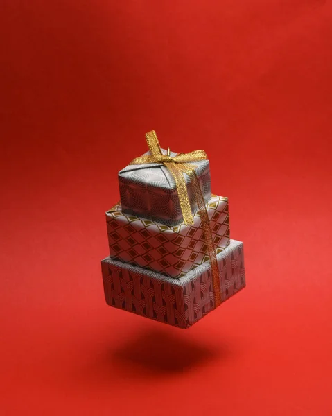 Stapel Kerstcadeaus Verpakt Een Boog Zwevend Een Rode Achtergrond Met — Stockfoto