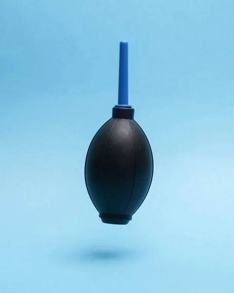 Enema for blowing dust from photographic equipment levitating on a blue background with a shadow