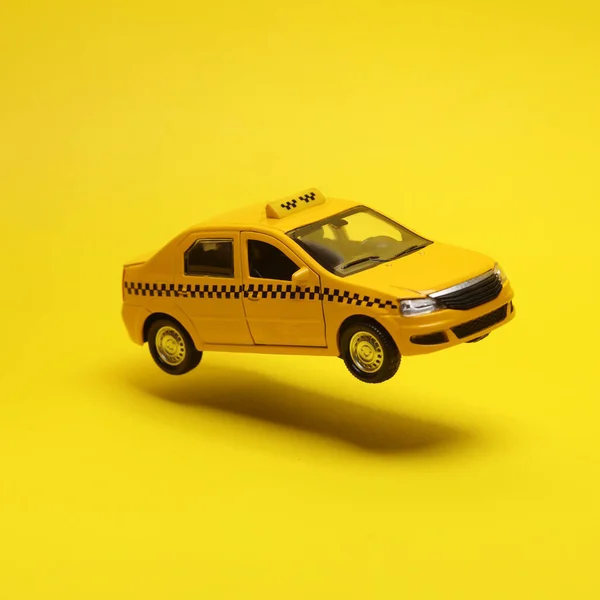 Minyatür Taksi Arabası Havada Süzülüyor Sarı Arka Planda Bir Gölgeyle — Stok fotoğraf