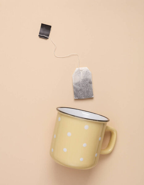 Cup with tea bag on a beige pastel background. Top view