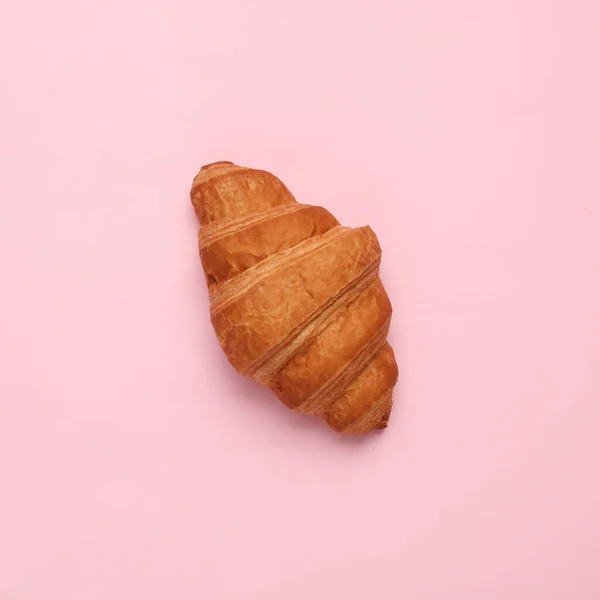 Appetizing croissant on a pink background