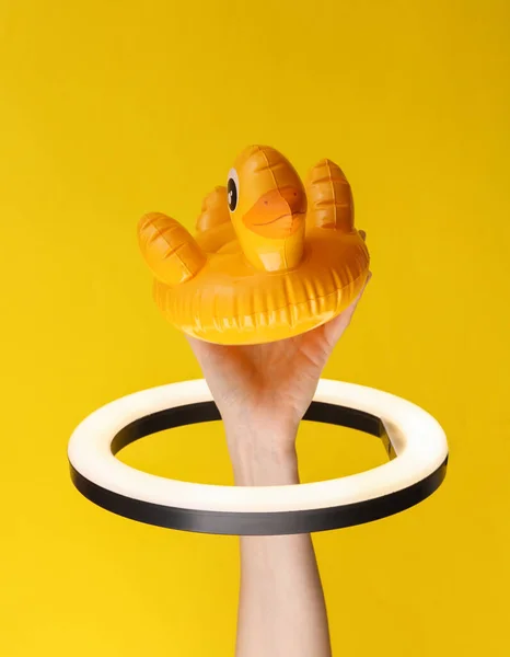 Frauenhand Hält Aufblasbare Ente Durch Led Ringlampe Auf Gelbem Hintergrund — Stockfoto