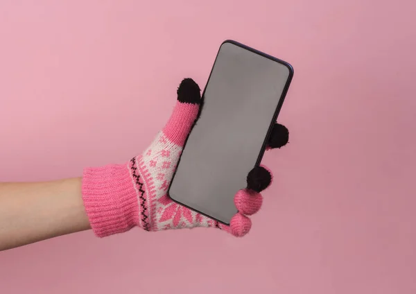 Damska Dłoń Ciepłych Rękawiczkach Dzianiny Wzorem Trzymającym Smartfona Różowym Tle — Zdjęcie stockowe