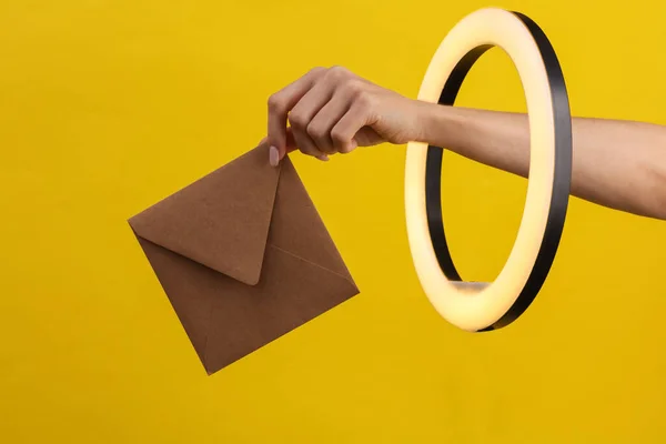 Woman Hand Holds Craft Envelope Led Ring Lamp Yellow Background — Stock Photo, Image