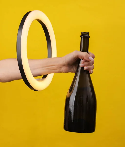 Kvinnans Hand Håller Champagne Flaska Genom Led Ring Lampa Gul — Stockfoto