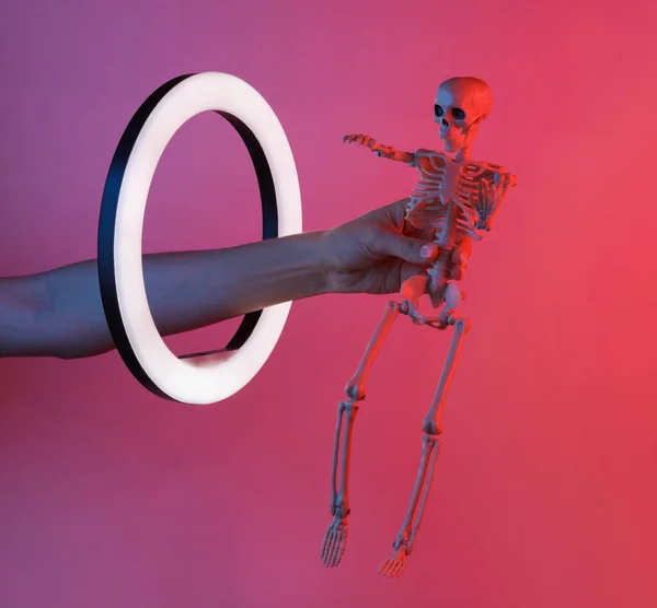 Kadının Eli Kırmızı Mavi Neon Işıklı Lamba Içinde Iskeleti Tutuyor — Stok fotoğraf
