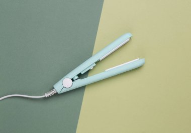 Yeşil arka planda mini saç düzleştirici. Üst görünüm