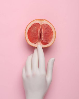 The mannequin's hand touches half of a grapefruit symbolizing the vagina. Sex and fruit concept