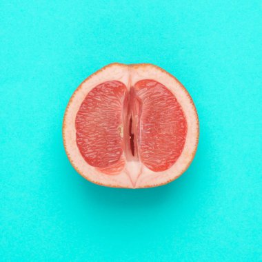 Gynecology, female intimate hygiene. Half of a ripe grapefruit symbolizing the female vagina on blue background. Creative idea, allegory, fresh idea. Top view