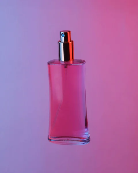 Eine Rosafarbene Parfümflasche Schwebt Der Luft Isoliert Blau Rotem Neonlicht — Stockfoto