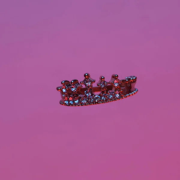 Crown with diamonds floating in the air, isolated in blue-red neon gradient light. Levitating objects. Minimal concept