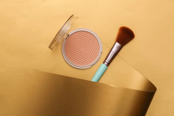 Powder box and makeup brush on a luxurious golden background