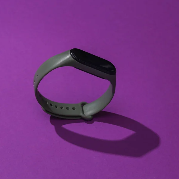Smart bracelet with long shadow on purple background