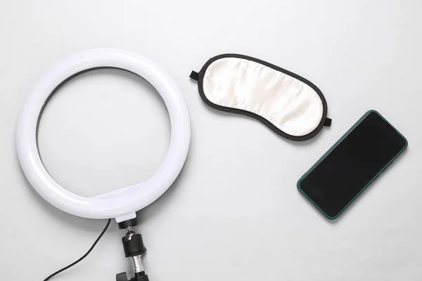 Led ring lamp with smartphone and sleeping mask on a gray background. Gear for blogging and vlogging. Top view