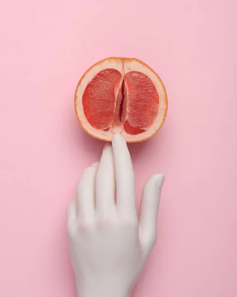 The mannequin\'s hand touches half of a grapefruit symbolizing the vagina. Sex and fruit concept