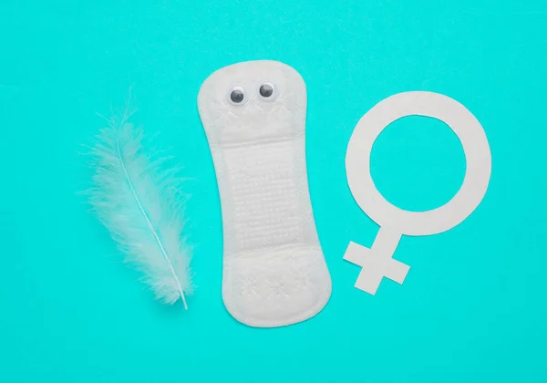 Intimate pad with eyes feather and venus female gender symbol on blue background. Feminine intimate hygiene concept