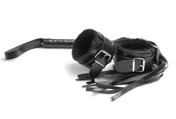 Deri kelepçeler ve beyaz arka planda bir seks dükkanından kırbaç.